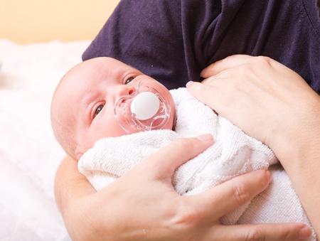 newborn baby (at the age of 7 days) in a knitted striped hat