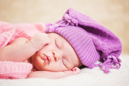 newborn baby (at the age of 14 days) sleeps in a knitted  hatの写真素材