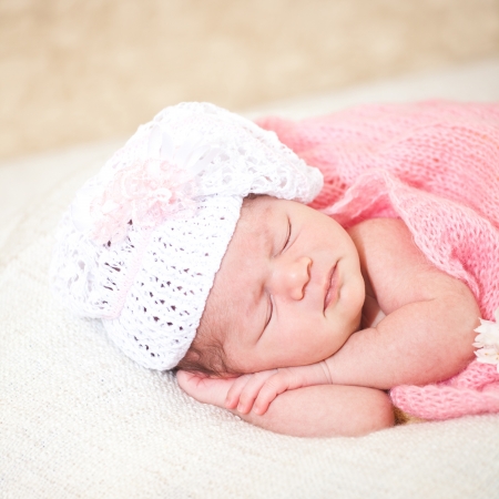 newborn baby (at the age of 14 days) sleeps in a knitted  hatの写真素材