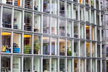 window of the multi-storey building of glass and steel office lighting and working people within