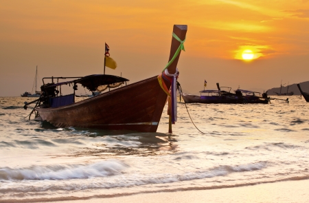 longtail boat standing near the shore at sunsetの写真素材
