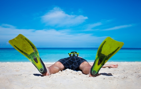 Tourist with flippers and mask relaxing on sand beach under blue sky, Thailandの写真素材
