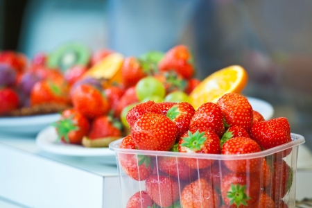 Fresh summer strawberry lies in a plastic tray on counter of buffetの写真素材