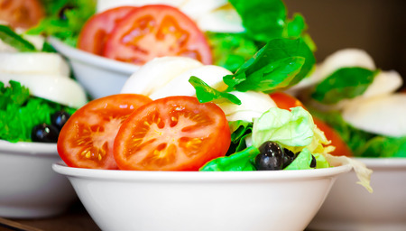 Italian salad from cherry tomatoes, a mozzarella and lettuce in a glass bowlの写真素材