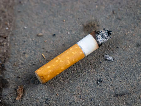 The burnt cigarette is lying on the gray groundの写真素材