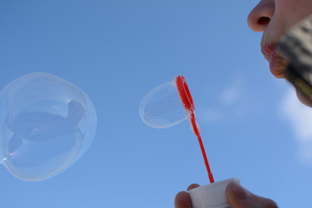 the girl starting soap bubbles against the blue skyの写真素材