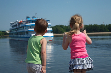 children in the port on the waterfront watching the outgoing shipの写真素材