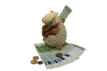 traditional piggy bank in the form of sheep with cash bills in euros isolated on whiteの写真素材