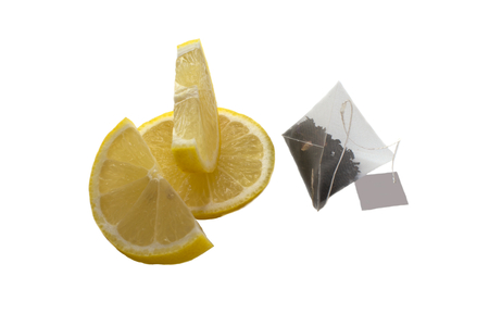 juicy slices of lemon and tea bag isolated on white backgroundの写真素材