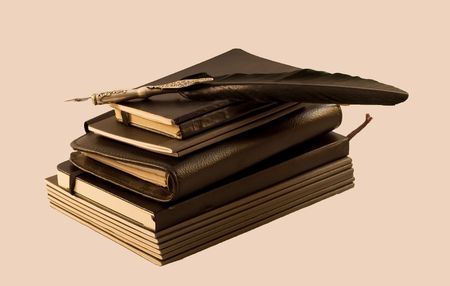 A pile of notebooks with a black old penの写真素材