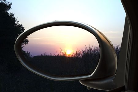 Sunset on a field, reflected in the rear view mirror of a carの写真素材