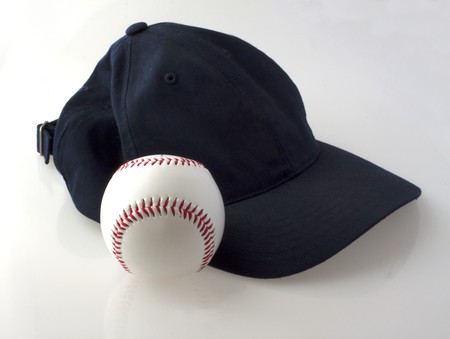 A baseball and a blue navy hat on a gray backgroundの写真素材