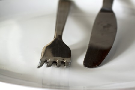 A fork and a knife over a white plate