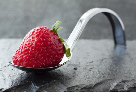 Strawberry over an elegant restaurant metal spoonの写真素材
