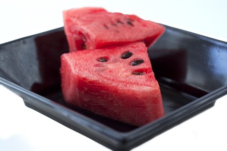 Two pieces of watermelon in a black plateの写真素材