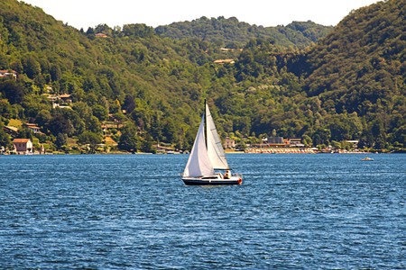 Lonely sail navigating near the border of a lakeの写真素材