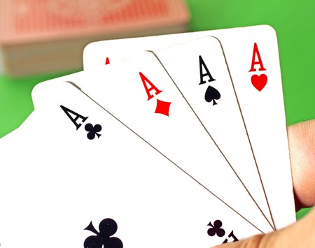 Four aces in male hand, green background