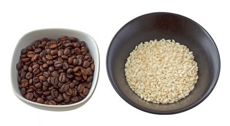 White cup full of coffee beans and black cup full of riceの写真素材