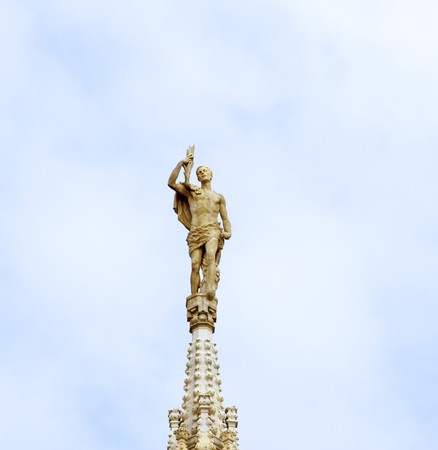 Statue on top of a "guglia" of Duomo of Milano, one of the most important monuments of christianityの写真素材