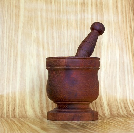 View of wooden mortar and pestle over light wood backgroundの写真素材