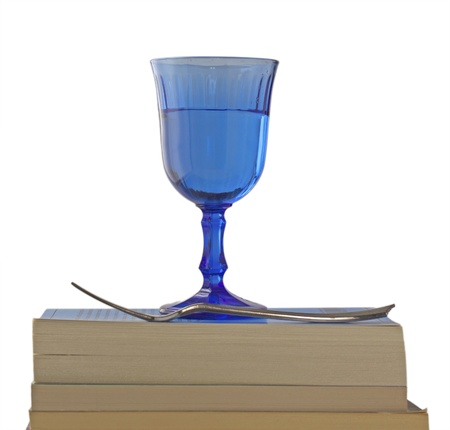 Some books in pile with a fork and a glass overの写真素材