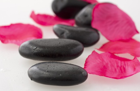 Some black stone for massage with petals of rose