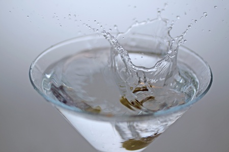 An olive falling in the glass of a cocktailの写真素材