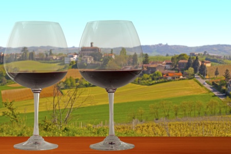 Red wine glasses on a wooden table, over a beautiful hills landscapeの写真素材
