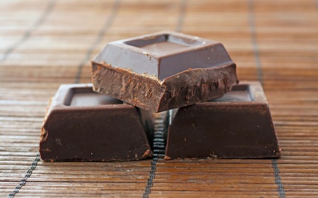 Three blocks of dark chocolate over wooden mat