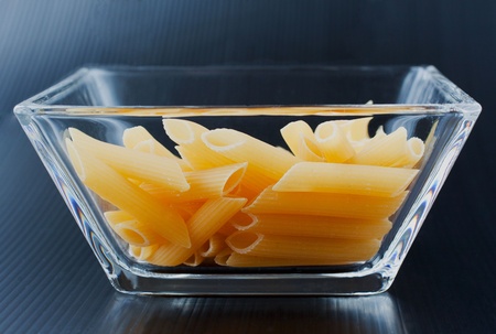 Typical Italian pasta ("mezze penne rigate") inside a glass square cupの写真素材