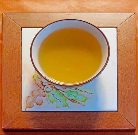 A cup of chamomile over a wooden decorated plateの写真素材