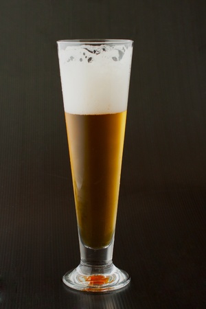 A glass of beer over a black backgroundの写真素材