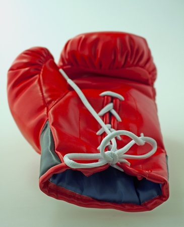 Single red and black boxe glove laying over gray backgroundの写真素材