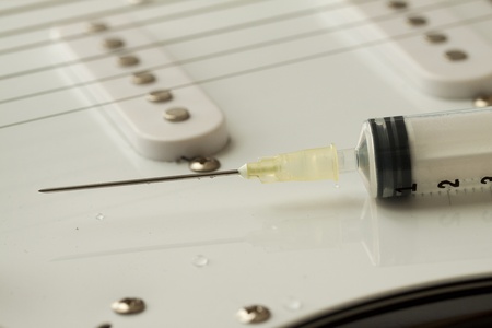 Closeup of a syringe over an electric guitarの写真素材