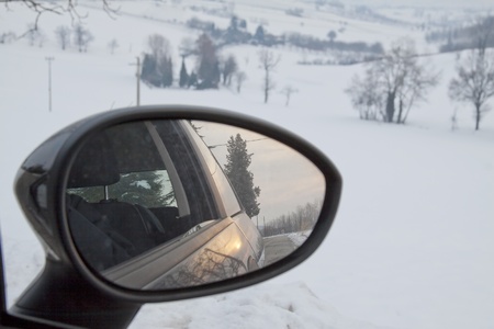 Sunset in the rearviewmirror of an automobile, in winter backgroundの写真素材