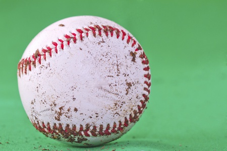 A dirty baseball over a completely green backgroundの写真素材