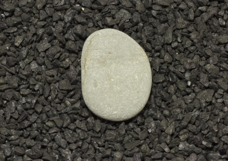 A gray stone over a background of little black stonesの写真素材