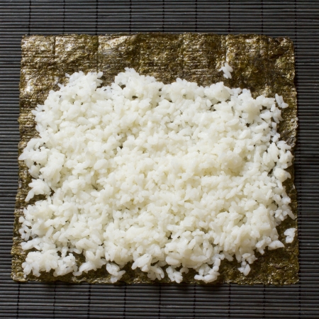 White rice laying over a seaweed for sushiの写真素材