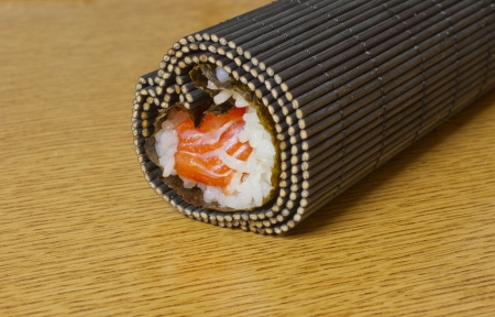 Cooking sushi: weed, rice and salmon rolled in a matの写真素材
