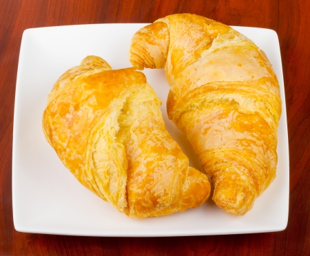 Two croissants on an elegant white plate, over wooden backgroundの写真素材