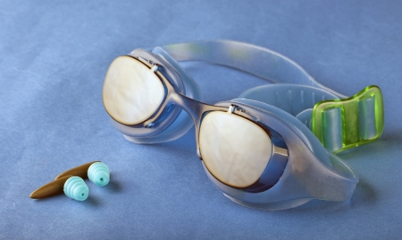A pair of swimming goggles over blue, with earplugsの写真素材
