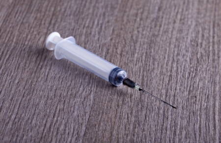 A white syringe over a wooden backgroundの写真素材