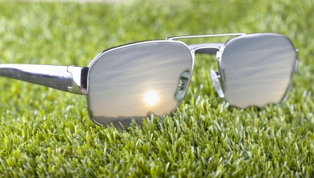 Shades laying over green grass with sunset on reflectionの写真素材