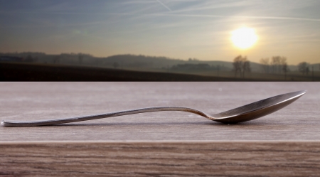 Close up of an iron spoon over a wooden backgroundの写真素材