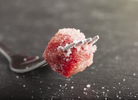 Piece of strawberry full of sugar on a forkの写真素材