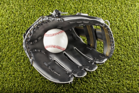 A baseball inside a black glove over green fieldの写真素材