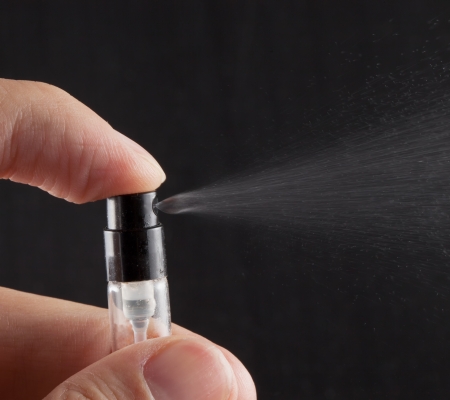 Male hand pushing on a little spray perfume