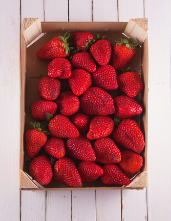 Strawberries in a box, over white wood, vertical imageの写真素材