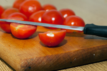 Small tomatoes cut in two over cutter, with bladeの写真素材