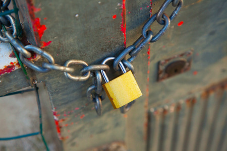 Golden lock closing a big chain over a fenceの写真素材